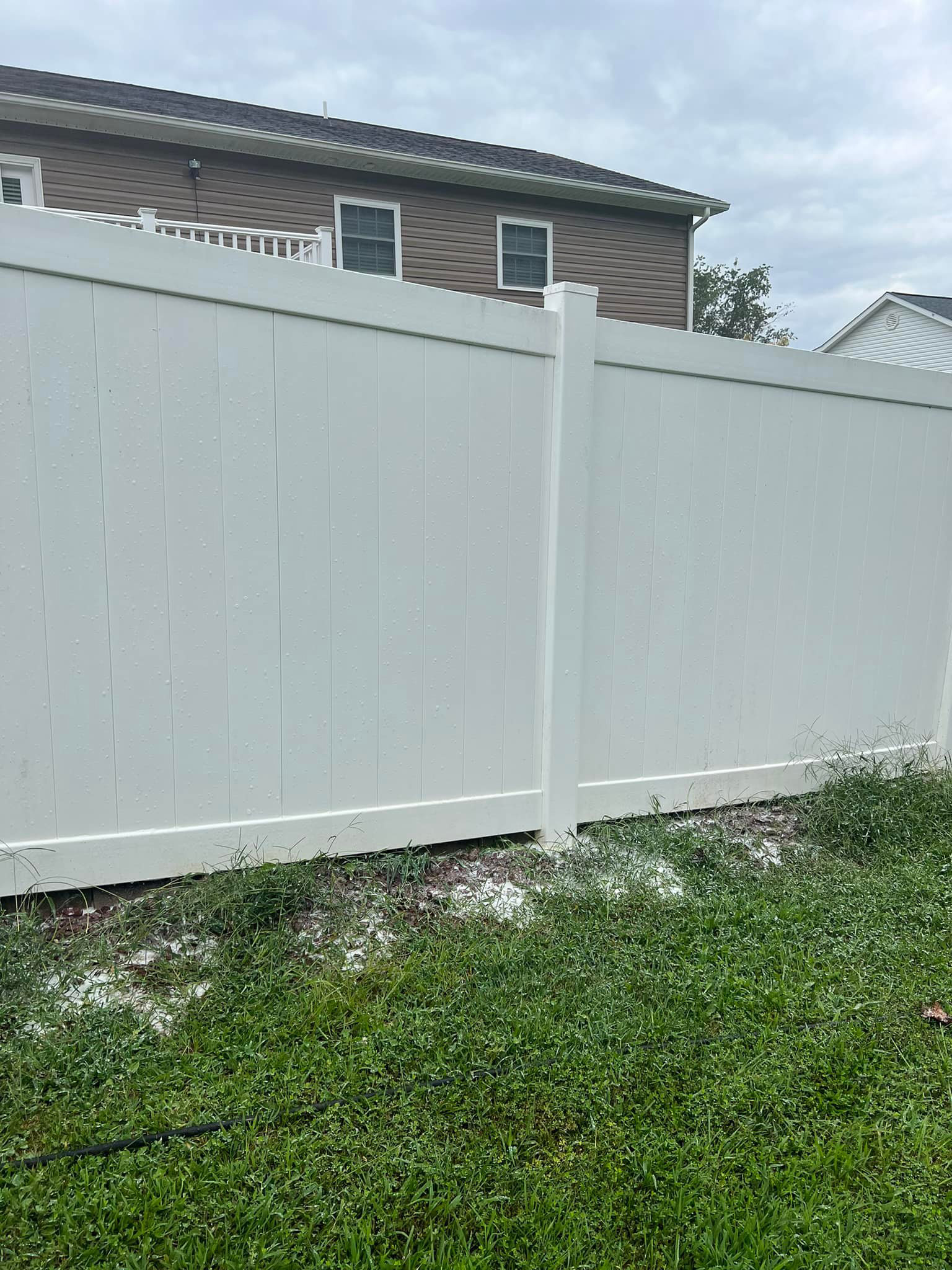 The same white fence with green mildew and stains removed, showing a clean and pristine surface.